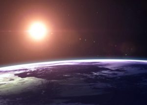 Earth from a low orbit with the sun in the distance