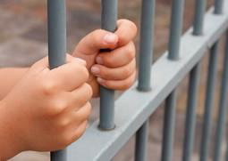 Hands grasping prison bars.