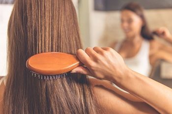 A woman brushing long brunette hair.