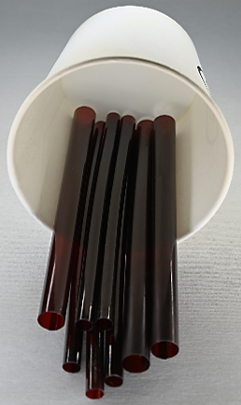 A group of dark brown straws of varying widths, sticking out of a cup laid on its side.
