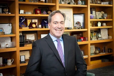 A man in front of shelves with knick-knacks wearing a suit and tie.