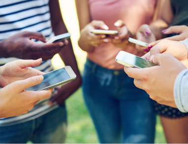 A group of young people standing in a circle with their cell phones out
