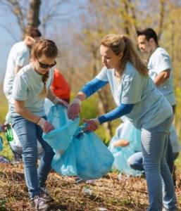 Two volunteers in blue shirts putting trash into large trash bags