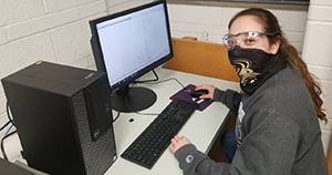 Student working on computer while wearing a mask