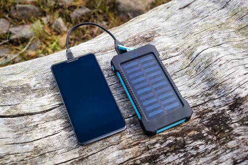 Solar powered charger recharging the battery of a cell phone
