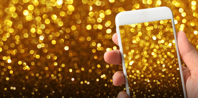 Person holding a phone in front of a gold glitter background