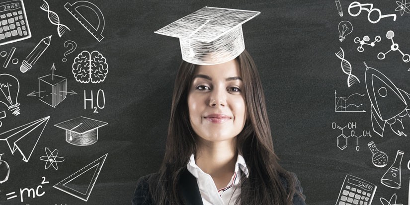 Person with graduation cap standing in front of chalkboard