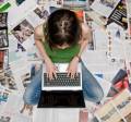 girl with laptop sitting on magazines