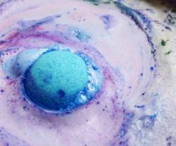 Pink and blue bath bomb dissolving in water