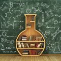 Bookcase in share of a flask in front of a chalkboard covered with chemistry and science related graphics