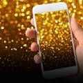 hand holding cell phone with gold sparkles
