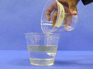Pouring oil into cup with water and corn syrup