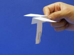 Hand holding the paper helicopter ready to drop it.
