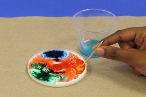 Touching toothpick with detergent to different drops of food coloring in the glue.