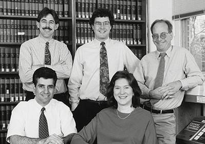 Five smiling members of the Merck team: three men in the back row, one man and one woman in the front row