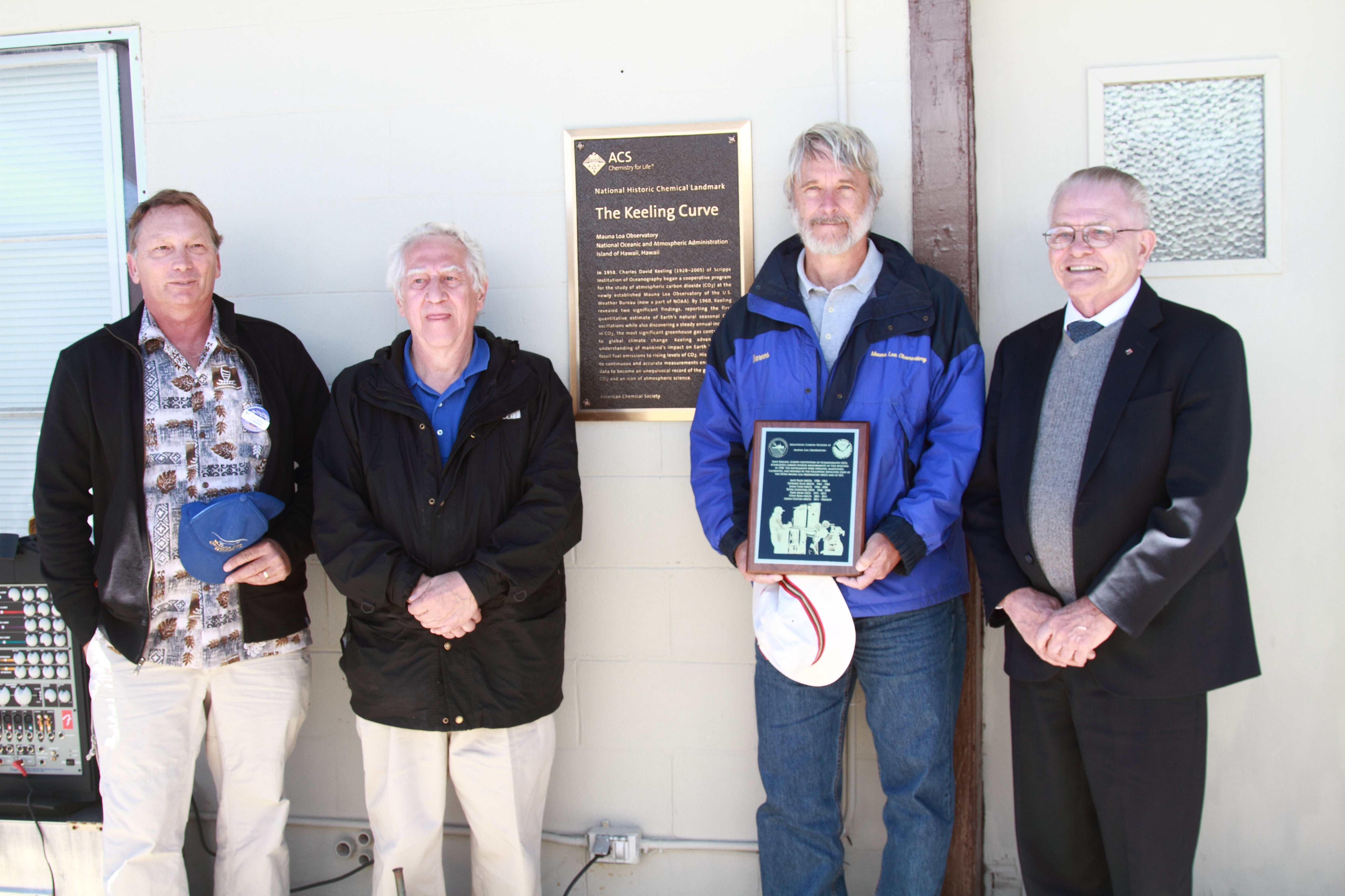 Four officials standing in front of a plaque