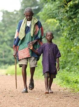 photo of boy leading man who is blind