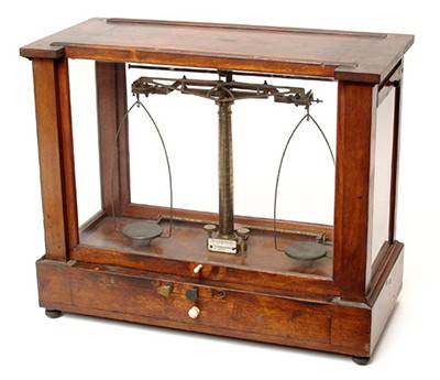 A wooden box holds an old metal analytical scale