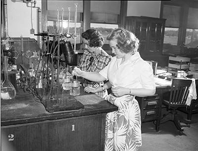 Black and white photograph of Marguerite Tenhunen and Dorothy Ferris at a lab bench