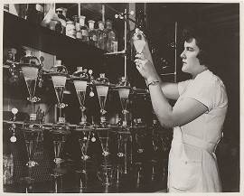 Female Upjohn chemist with glass flasks containing steroid intermediates produced by microorganisms
