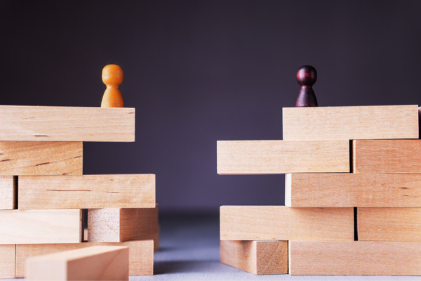 Photo of chesss pawns atop wooden blocks forming a canyon on a tabletop, representing the concept of the aspiration gap.