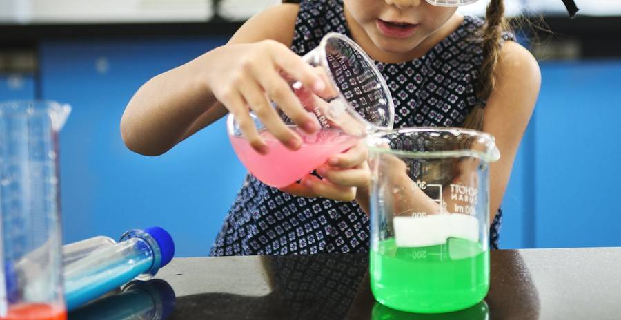 kindergarten girl mixing liquids in beakers
