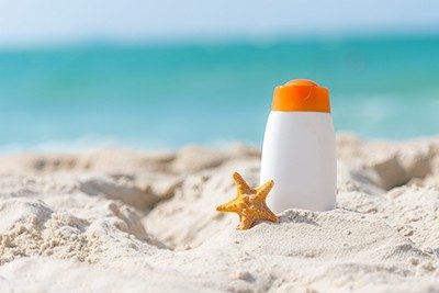 A tube of sunscreen sitting in the sand of a beach.