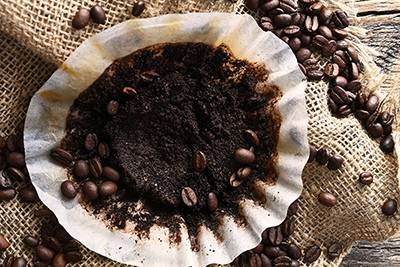 Overhead view of coffee filter with used coffee grounds in it on a burlap coffee bean bag in the background