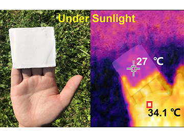 Two images side-by-side. On the left, a hand holding the aerogel: a small square piece of white material. On the right, a heatmap of the image with the piece of material staying cool in the sun.
