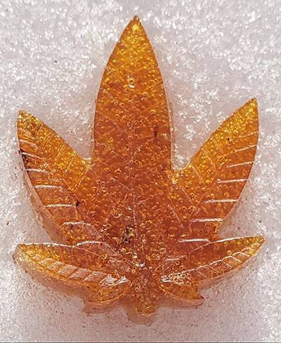 Amber colored polymer molded in the shape of a cannabis leaf.