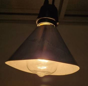 Lampshade surrounds a brightly glowing lightbulb.