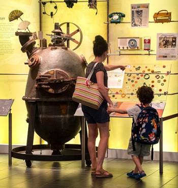 A woman and child look at equipment and products in a museum.
