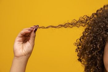 Person with curly hair stretches out one strand of it.