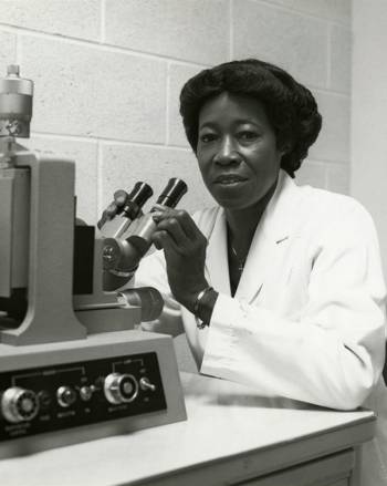 A Black woman in a lab coat with scientific equipment