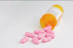 pink pills spilling from pill bottle onto white surface