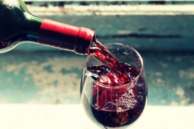 Bottle of red wine poured into a wine glass