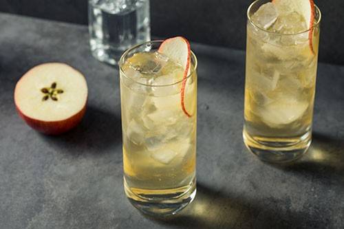 glasses of apple spirits with sliced apple next to them