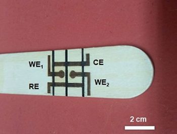 A tongue depressor with two laser-formed electrochemical cells on it.