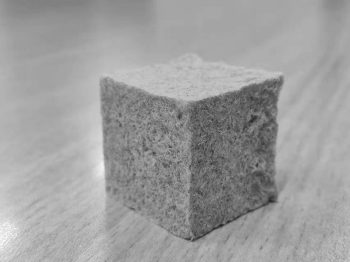 A cube of grey-colored porous, papery foam.
