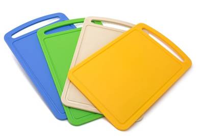Four plastic cutting boards in periwinkle blue, bright green, tan and light orange are fanned out on a plain background