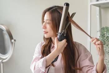 Woman styling hair with a curling iron