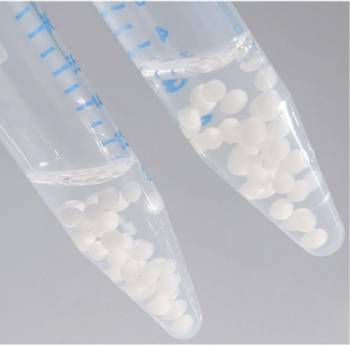 Two centrifuge tubes hold clear liquid with white spheres evenly distributed throughout 