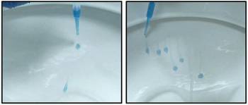 Blue liquid being squeezed out of droppers onto the inside of toilet bowls. On the left bowl are two droplets, and on the right are six droplets trailing down. 