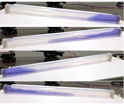 A series of four time-lapse photos showing a transparent tube containing blue-dyed water being rocked back and forth on a laboratory bench.