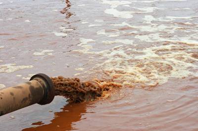 A pipe releasing dirty brown water into a river.