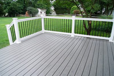 A backyard deck made from composite material with white fencing around the side.