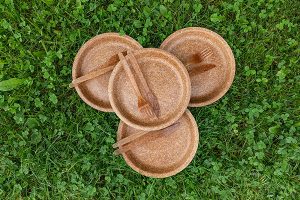 Four brown plates and utensils sitting outside.