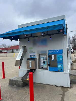 A small tan building with a water dispenser and an ice dispenser on the outside wall.