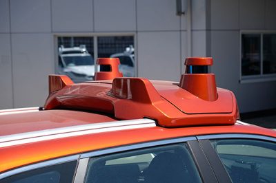 Two lidar sensors and a camera mounted to the roof of a self-driving car.